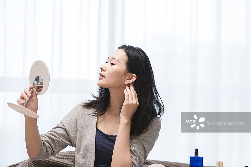 青年女子在客厅照镜子戴耳环图片素材
