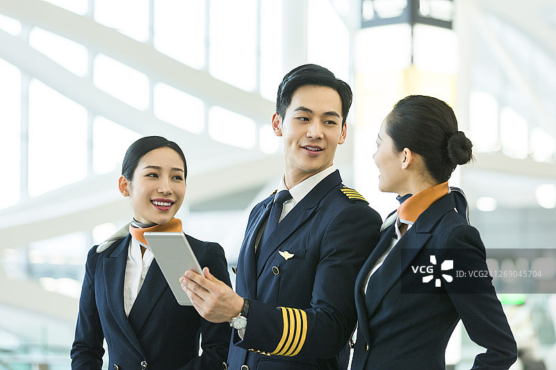 飞机机长和两名空姐在机场使用平板电脑沟通工作图片素材