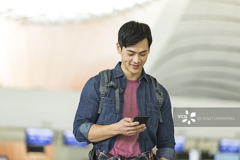 青年男子使用手机在机场图片素材