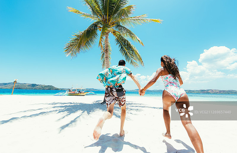 在热带海滩上奔跑的情侣的背面图片素材