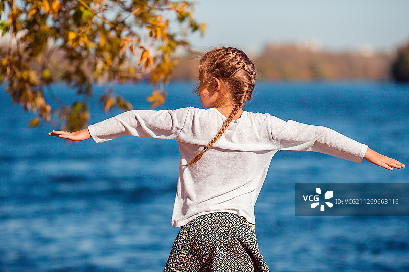 女孩在河岸上伸出双臂的背影图片素材