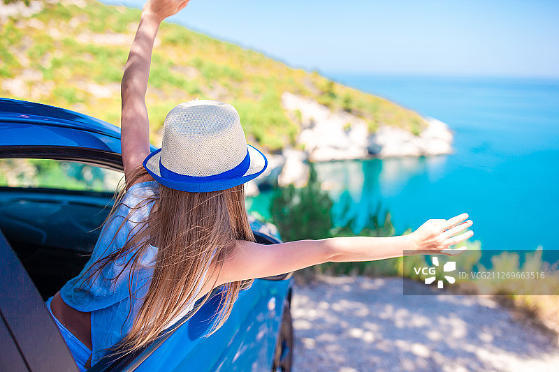 小女孩在汽车里度假旅行，背景是美丽的风景图片素材
