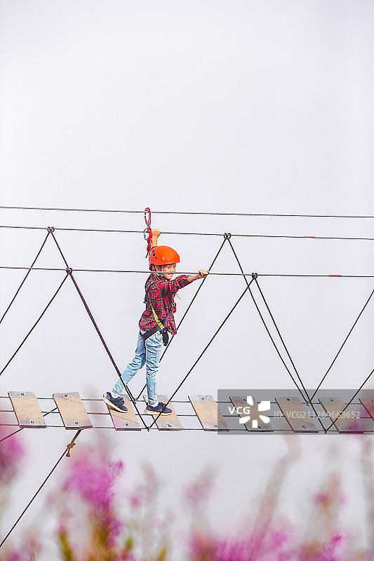 女孩在山里的悬索桥上兴奋地散步图片素材