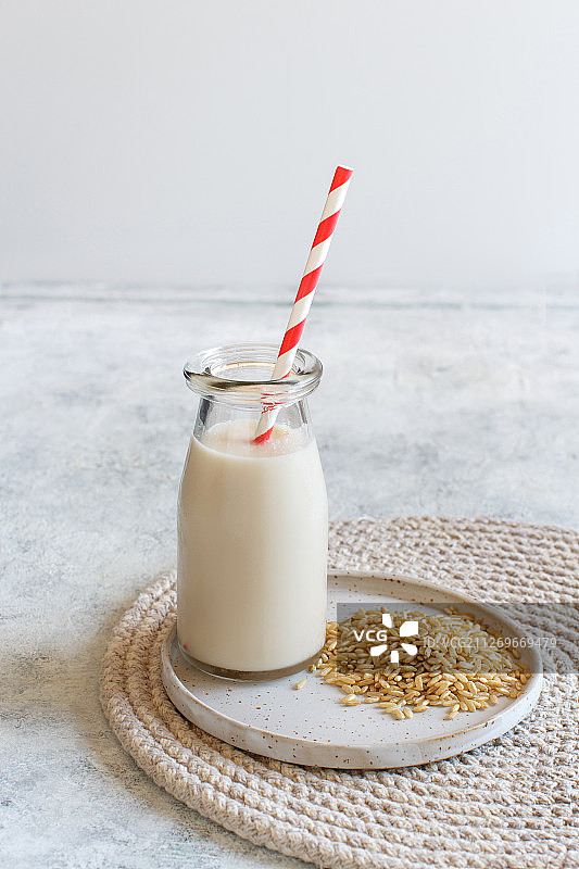 瓶装纯素米浆和盘中糙米的特写图片素材