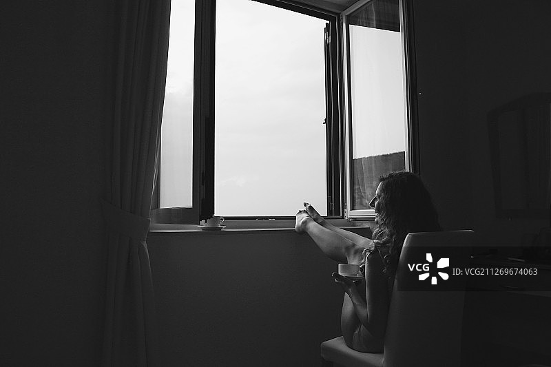黑白照片：年轻女人在窗边喝咖啡图片素材