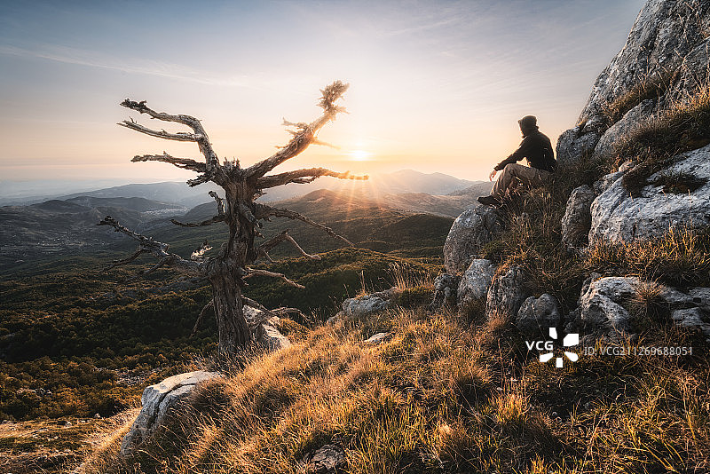 男子坐在岩石上观看日出，意大利莫拉诺卡拉布罗图片素材