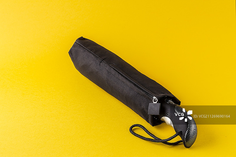 黄色背景上的黑色雨伞图片素材