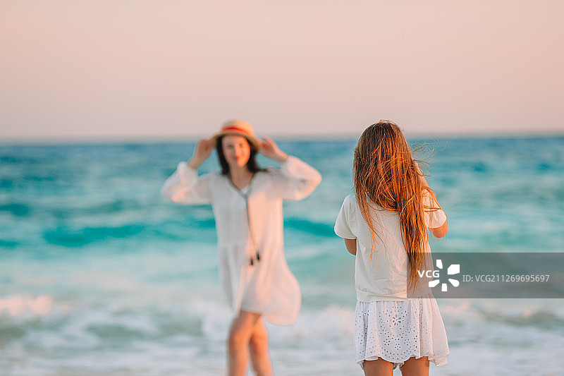 女孩在热带海滩给妈妈拍照图片素材