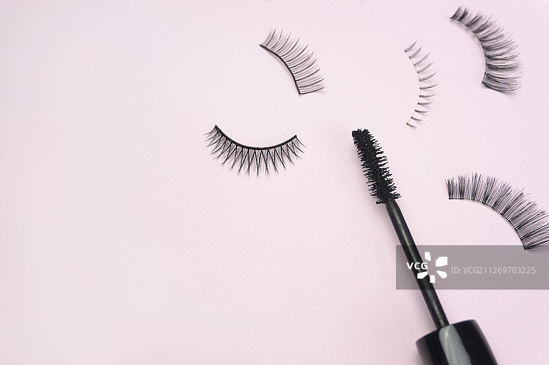 粉色背景上的假睫毛和睫毛膏图片素材