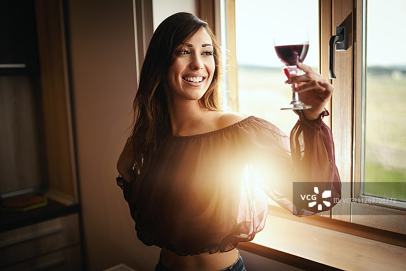 年轻快乐的女人举起一杯葡萄酒图片素材