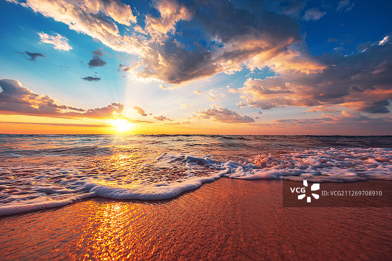 多云天空下，海上日出与海岸线图片素材