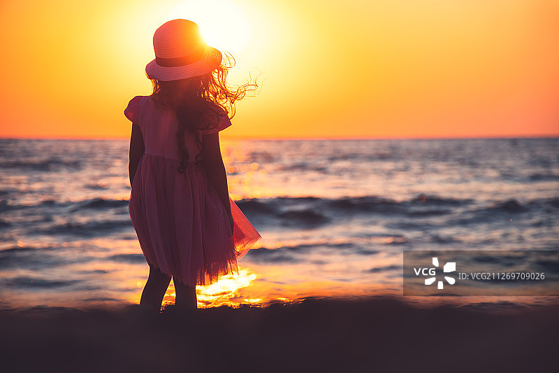 在海滩上看日出的粉色连衣裙小女孩（6-7岁）图片素材