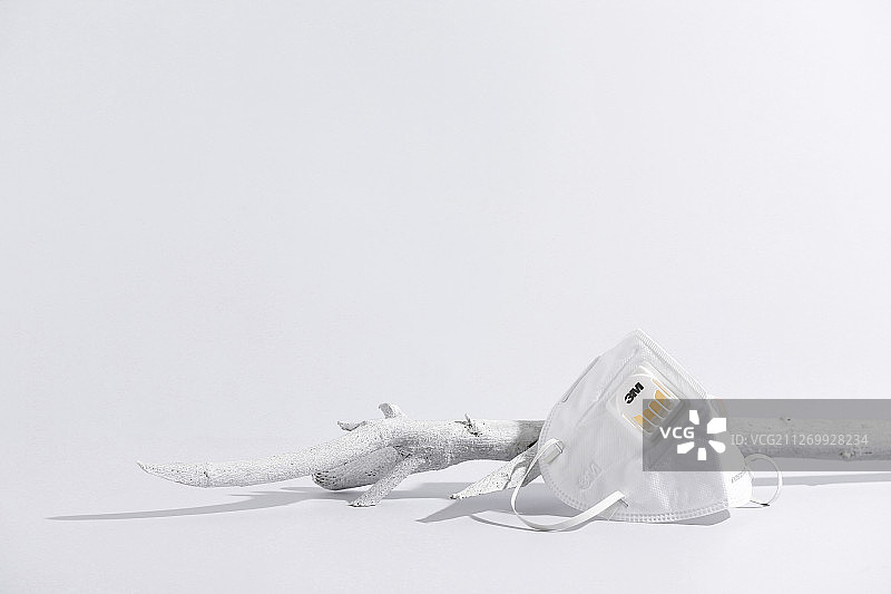 白色背景上靠着树干的N95口罩图片素材