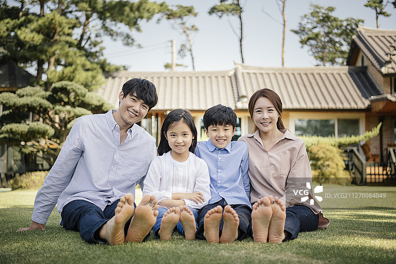 家庭花园里，一家人赤脚坐在草坪上摄影图片素材