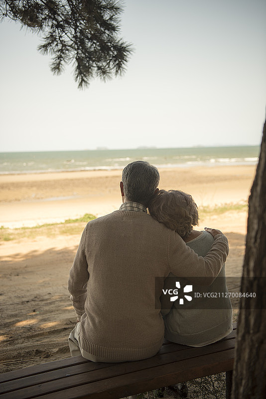 坐在海滩长椅上的老年夫妇摄影图片素材