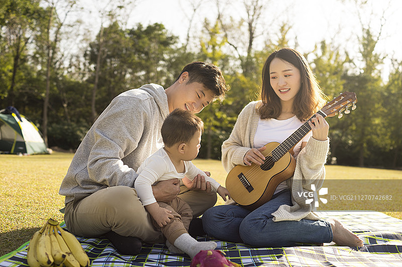 温馨的一家三口在草地上野餐图片素材