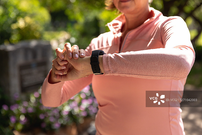 在公园使用智能手表的跑步女人图片素材