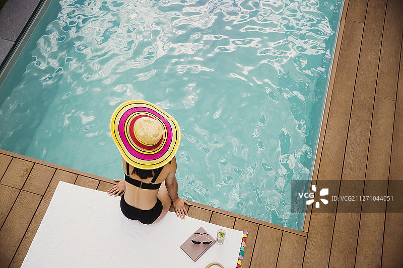 戴太阳帽和比基尼的女人在泳池边放松图片素材