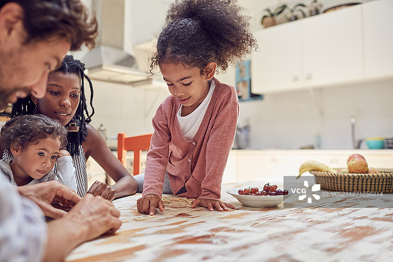 年轻家庭在桌旁玩拼字游戏图片素材