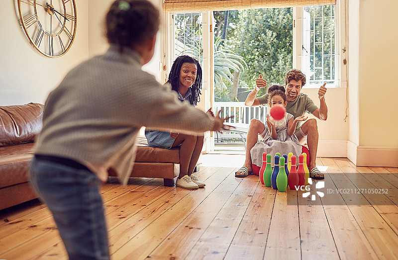 年轻家庭在客厅里玩保龄球图片素材
