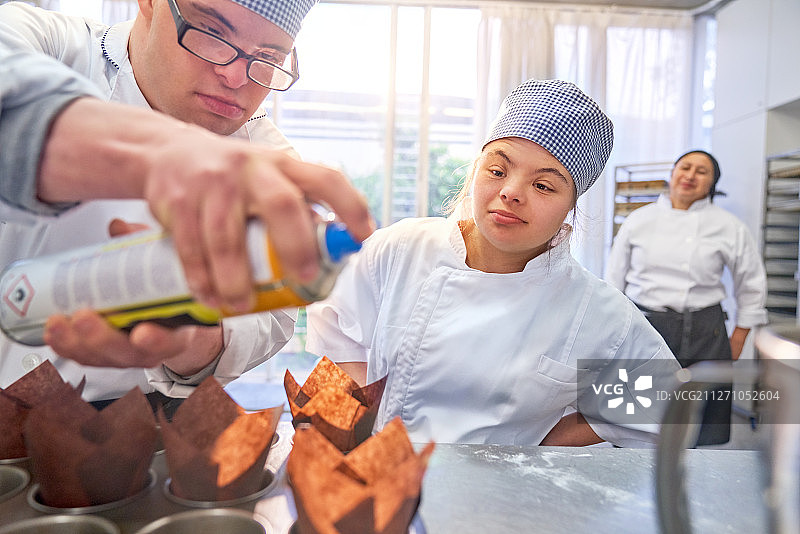 患有唐氏综合征的年轻学生在厨房里烤松饼图片素材