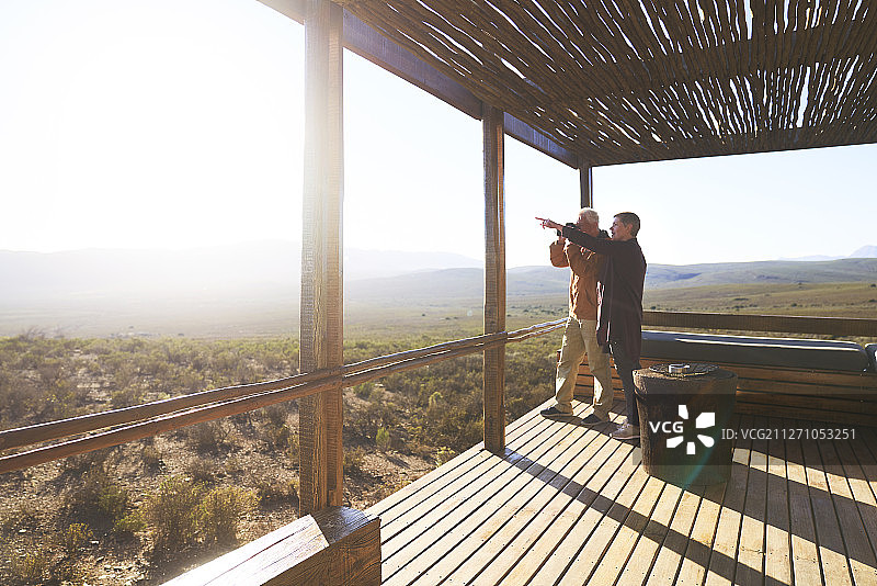 老年夫妇在游猎小屋阳台上欣赏阳光明媚的景色图片素材