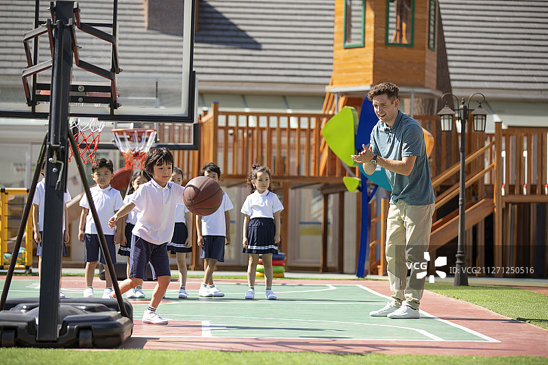 外教和孩子在操场打篮球图片素材