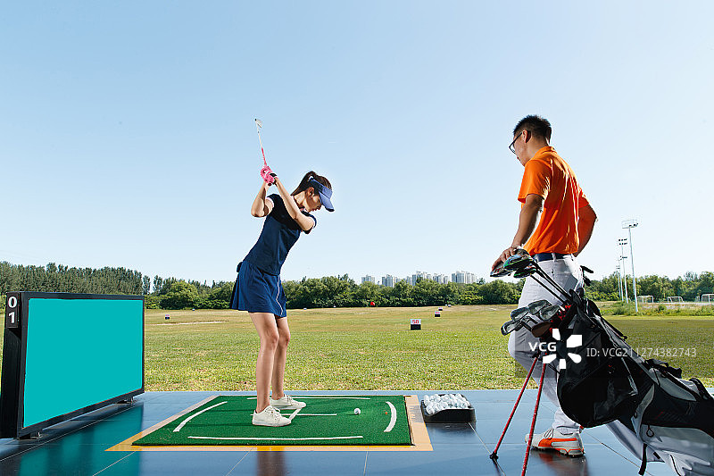 练习场上教练指导青年女人打高尔夫图片素材