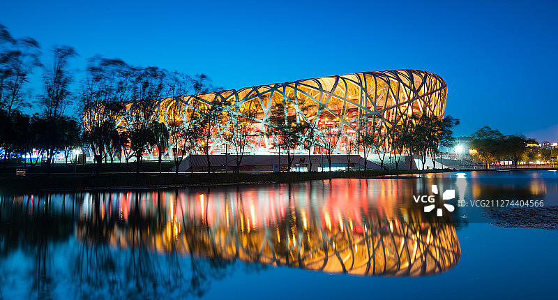 国家体育场（鸟巢）钢结构倒影清晰可见，透出暖黄色灯光图片素材
