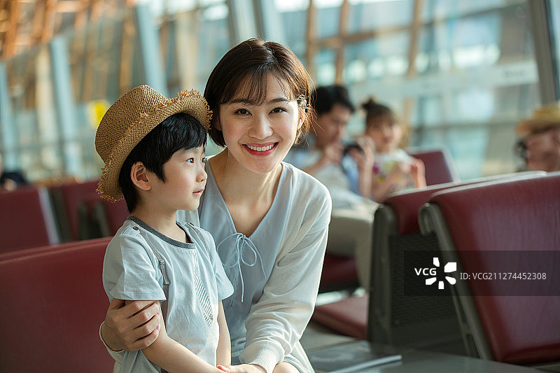 年轻妈妈和儿子坐在机场候机厅图片素材
