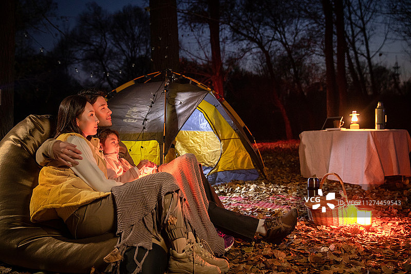幸福的一家三口夜晚在野外露营图片素材