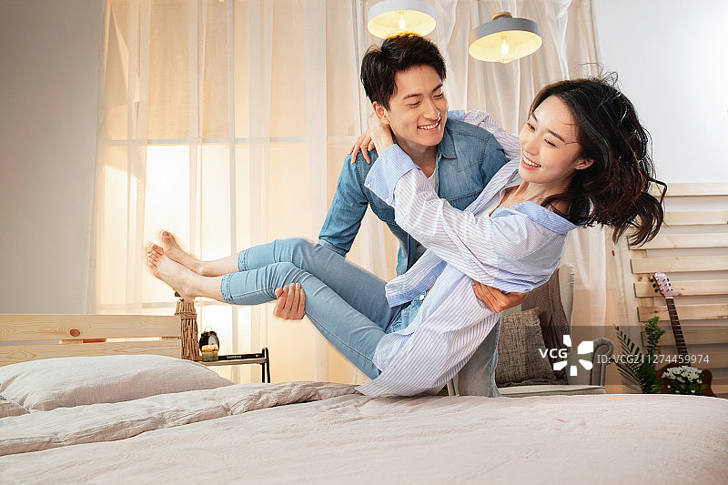 年轻丈夫把妻子抱到床上图片素材
