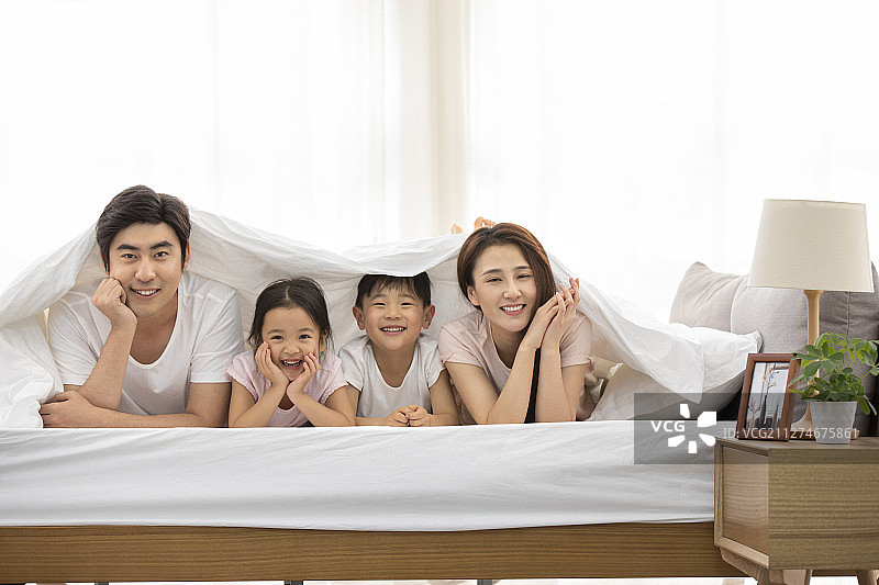 快乐的年轻家庭在床上图片素材