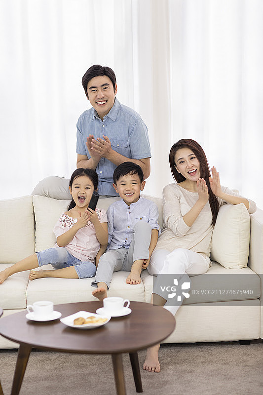 快乐的年轻家庭在客厅看电视图片素材