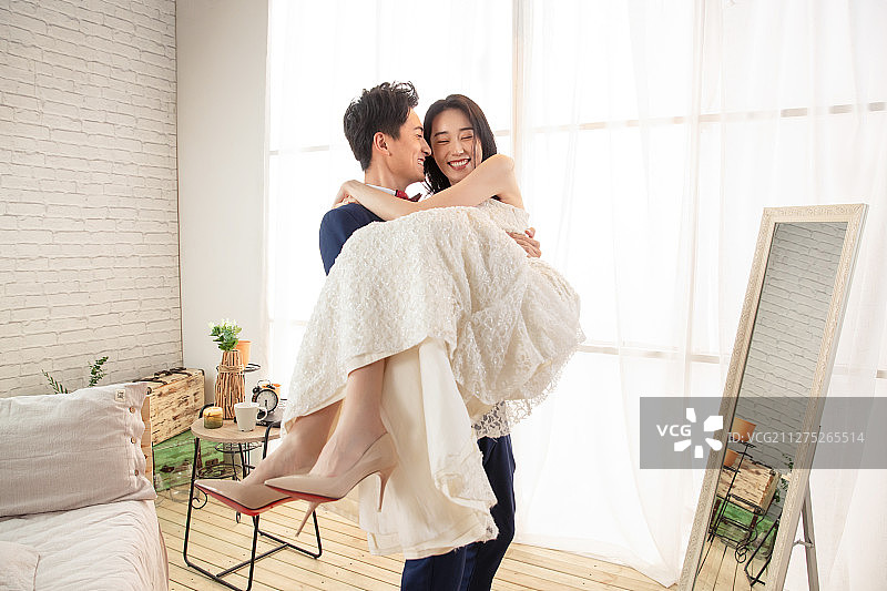 卧室里幸福的丈夫把妻子抱起来图片素材