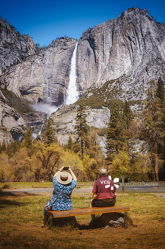 优胜美地国家公园，两个老人在长椅上坐着欣赏上下瀑布图片素材