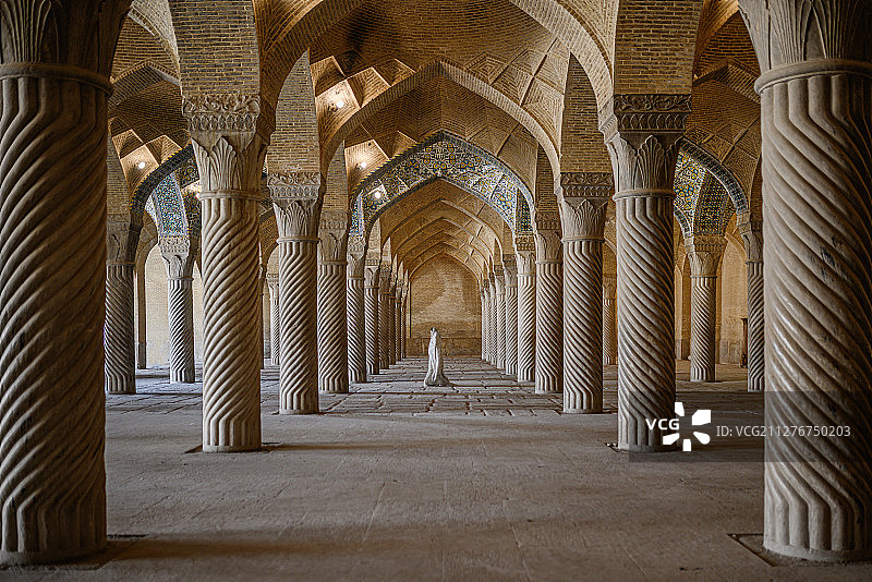 伊朗设拉子的瓦基尔清真寺，一位游客穿着长袍走过祈祷大厅图片素材