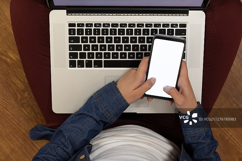 年轻男人在家使用智能手机和笔记本电脑图片素材