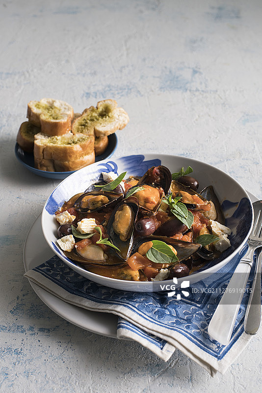 白葡萄酒地中海贻贝配卡拉马塔橄榄、番茄、菲达奶酪和罗勒图片素材