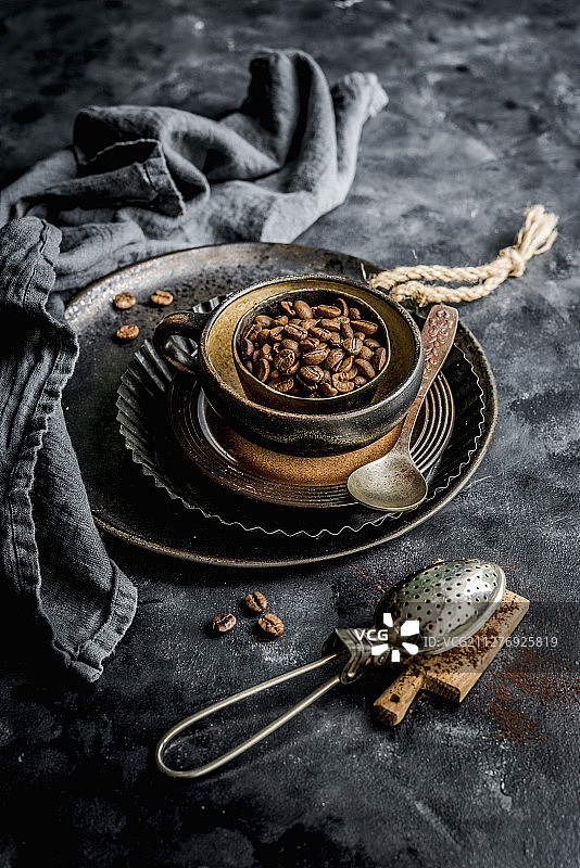 碗里的咖啡豆，前景是可可粉筛子图片素材