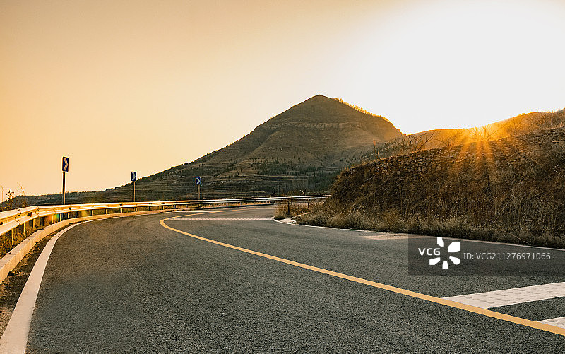 日落时洒满阳光的无人山间公路图片素材