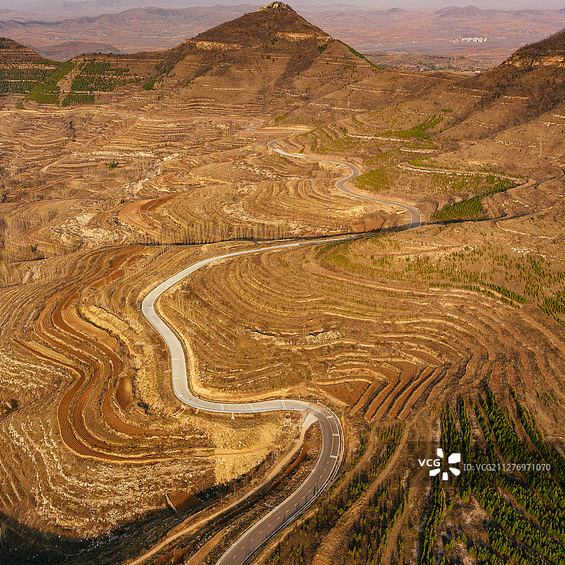 航拍层层叠叠的绿色山谷中一条蜿蜒的公路图片素材
