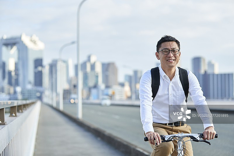 在日本大阪市中心骑自行车的成熟日本男人图片素材