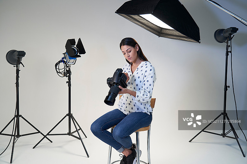 在影棚用相机和照明设备进行拍摄的女摄影师图片素材