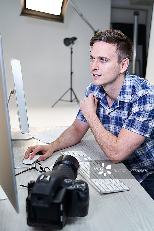 在工作室里查看电脑上照片的男摄影师图片素材