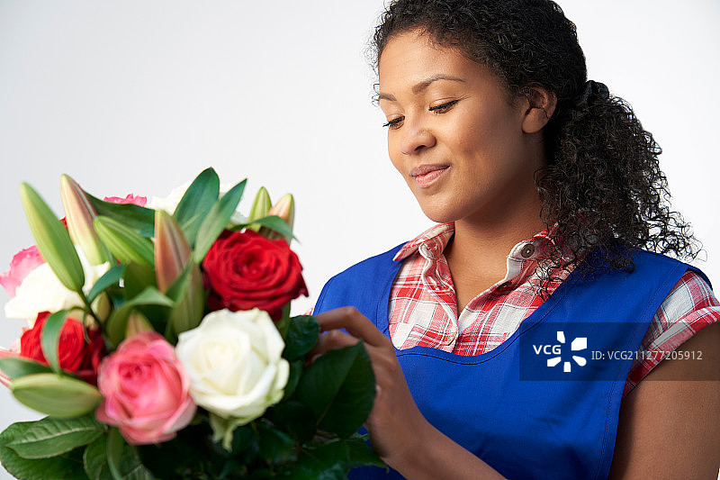 在白色背景下整理百合和玫瑰花束的女花艺师影棚照图片素材