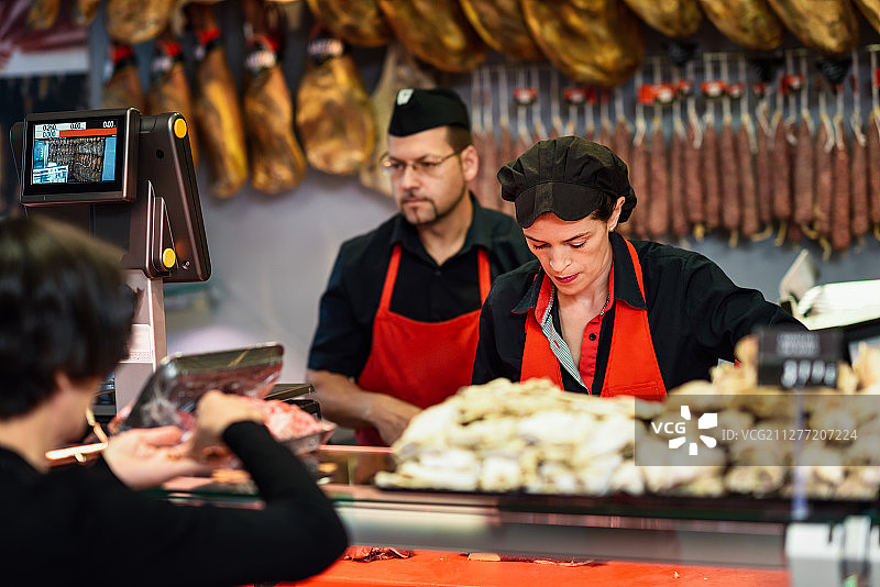 肉铺店员为顾客称重肉并收费图片素材