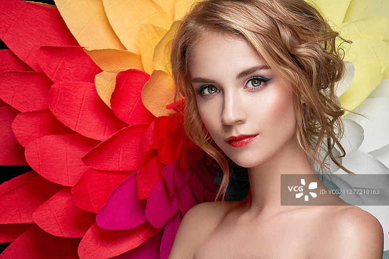 以大型花朵为背景的美丽女人：彩虹菊花夏日美女模特，发型精致，妆容时尚图片素材