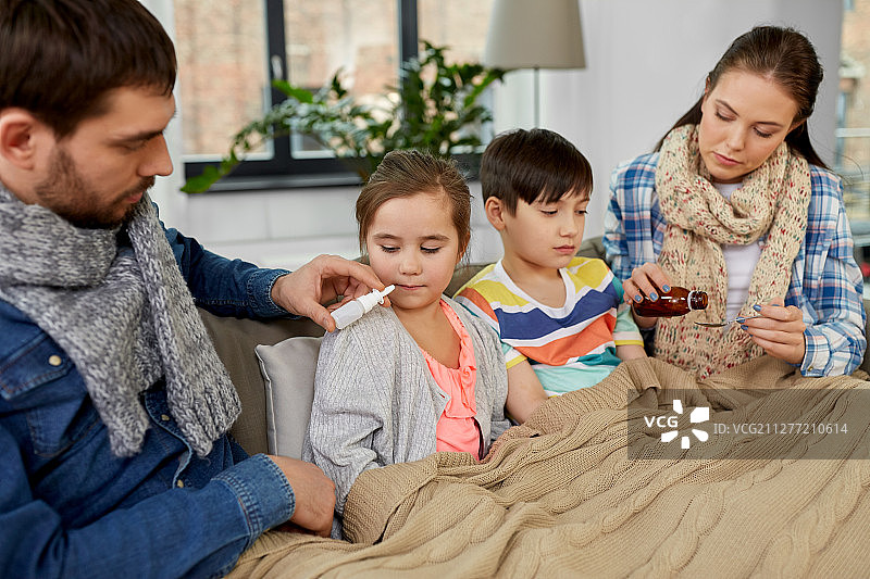 一家人在家照顾生病的孩子，父亲拿着药，母亲拿着鼻腔喷雾剂图片素材