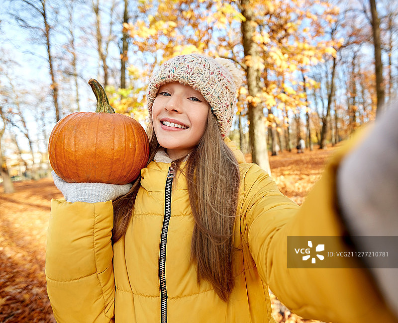 秋日公园里用南瓜自拍的快乐女孩图片素材